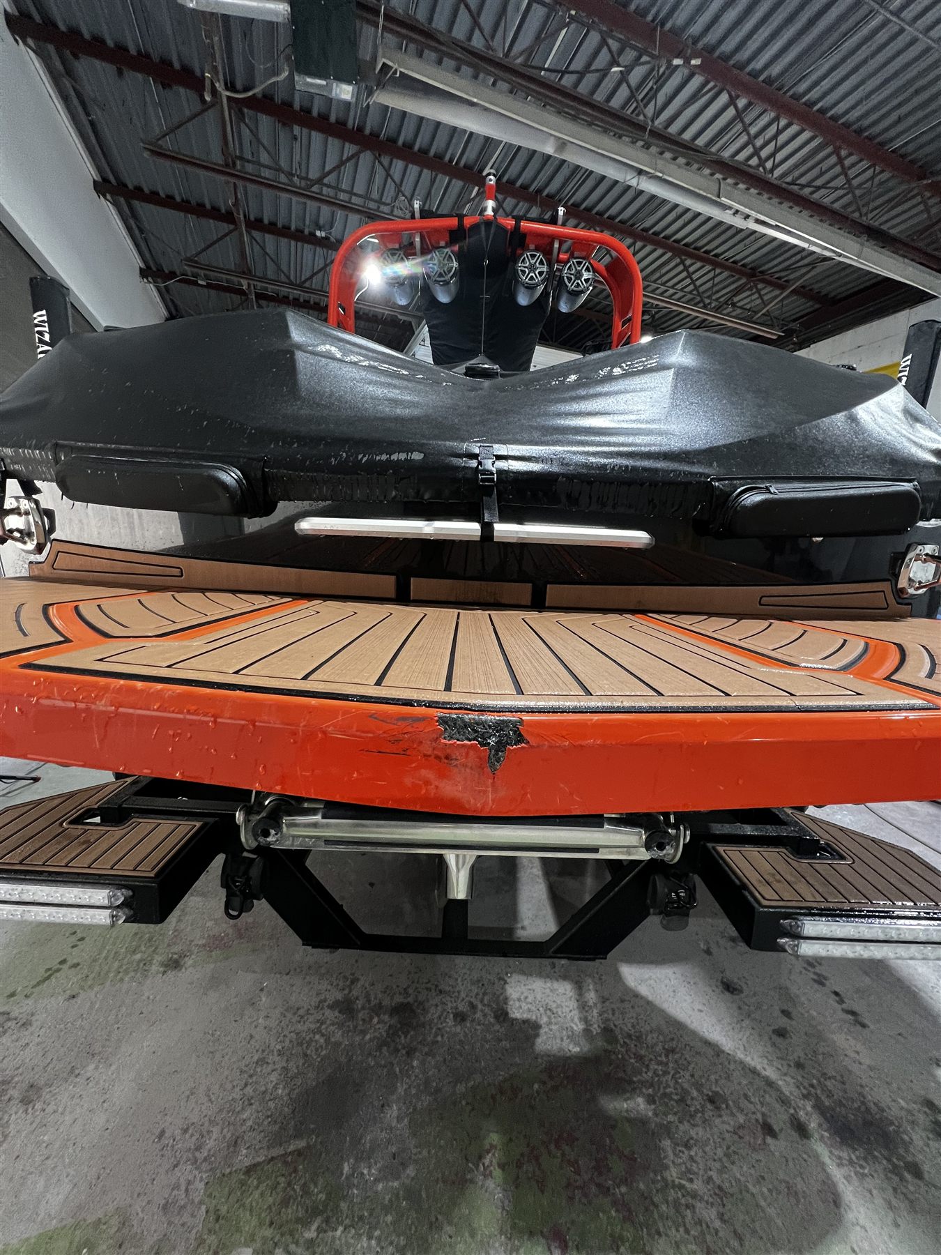 Orange boat swim platform with impact damage before Waterline repair