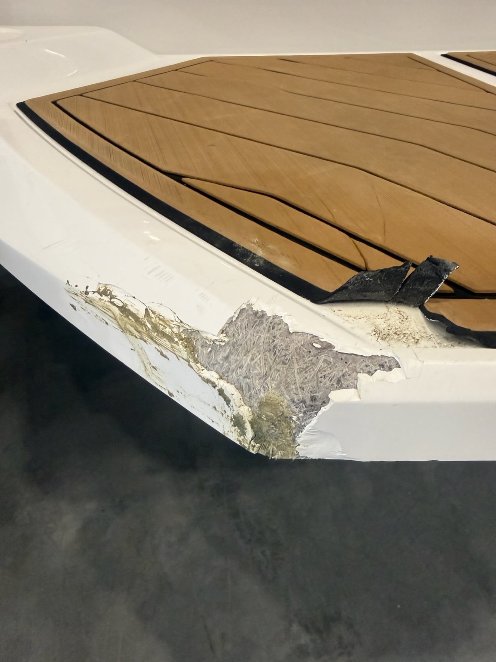 Tan-deck swim platform with extensive exposed fibreglass damage before repair
